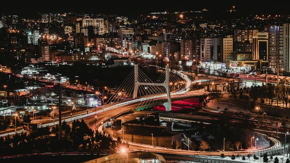 Una vista nocturna de una ciudad con un puente en primer plano