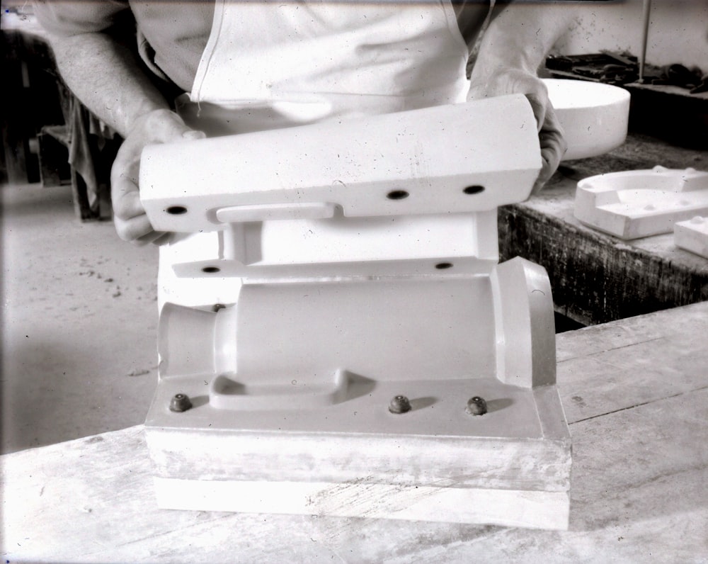 a black and white photo of a man working on a machine
