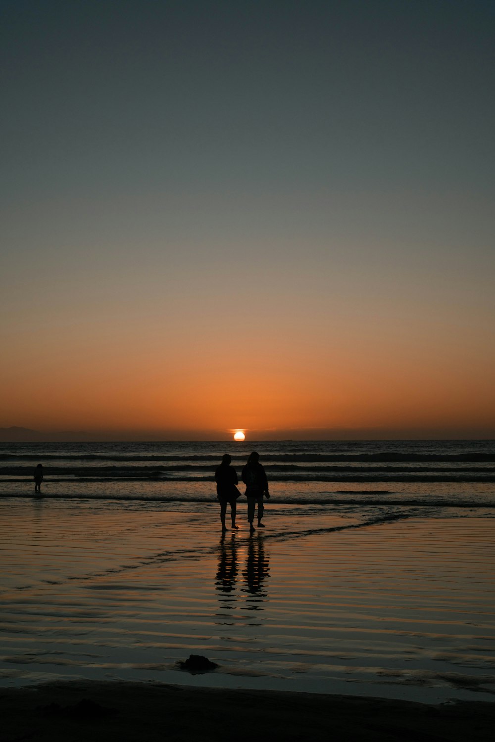 a couple of people standing on top of a beach