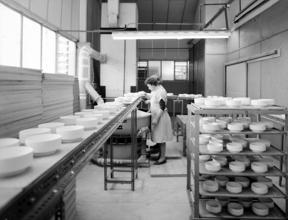 a black and white photo of a woman in a kitchen