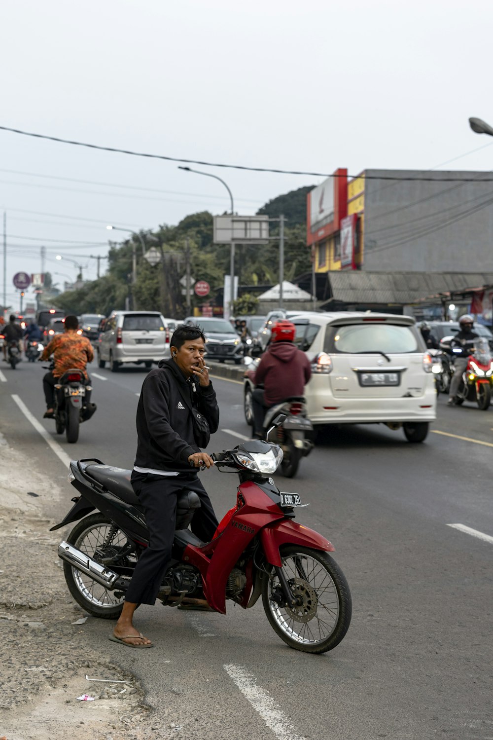 a man riding a red motorcycle down a street