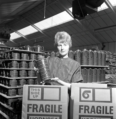 A professional mover carefully wrapping a fragile antique vase with bubble wrap in a bright, organized packing room.