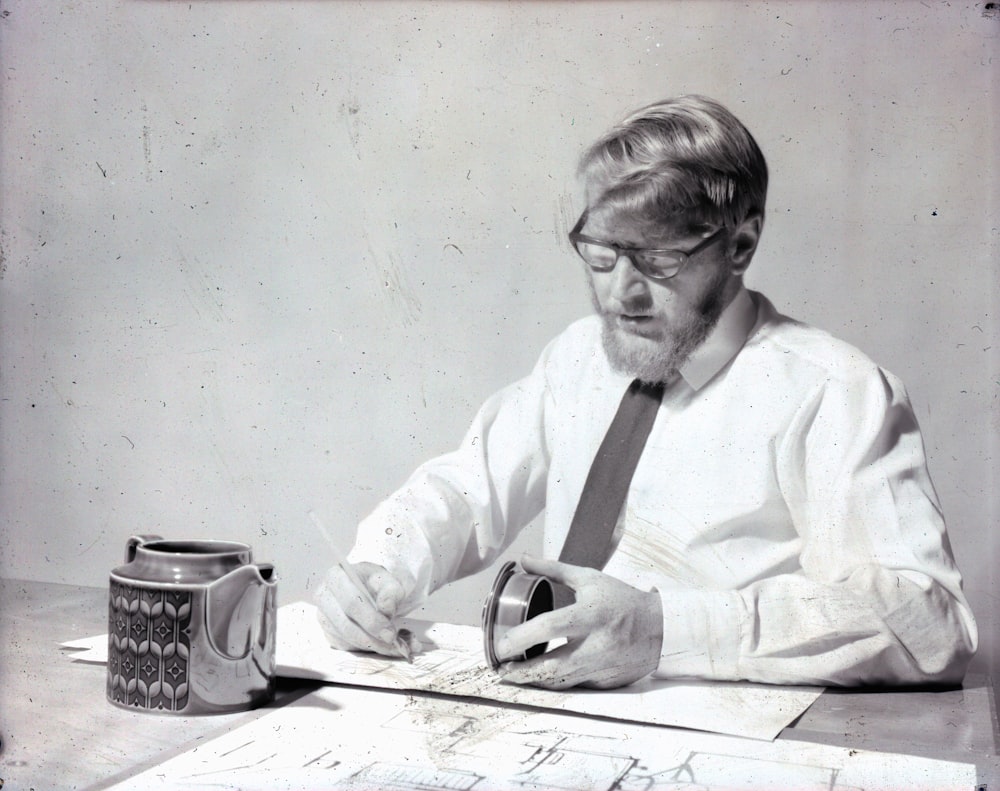 a man sitting at a table in front of a coffee mug