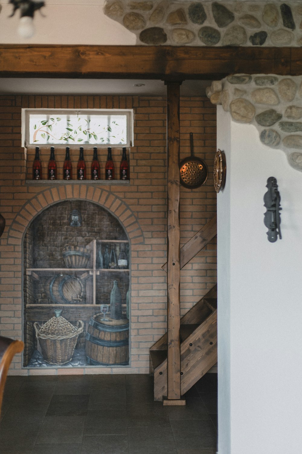 a room with a brick fireplace and wine bottles on the wall