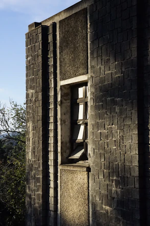 Close-up of natural clay brick cladding installed on a modern Bangalore office facade under bright sunlight.