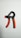 A handheld grip strengthener with black and orange handles is positioned against a plain white background. The design features a spring mechanism at the top, allowing for adjustable resistance.