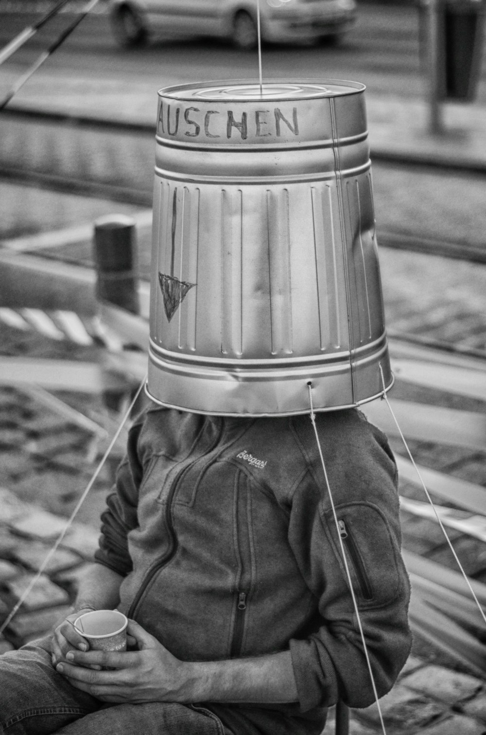 a person sitting on the ground with a bucket on their head