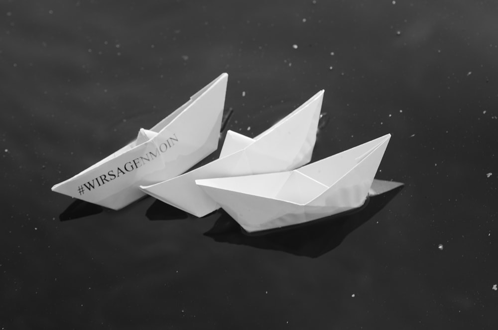three paper boats floating on top of a body of water
