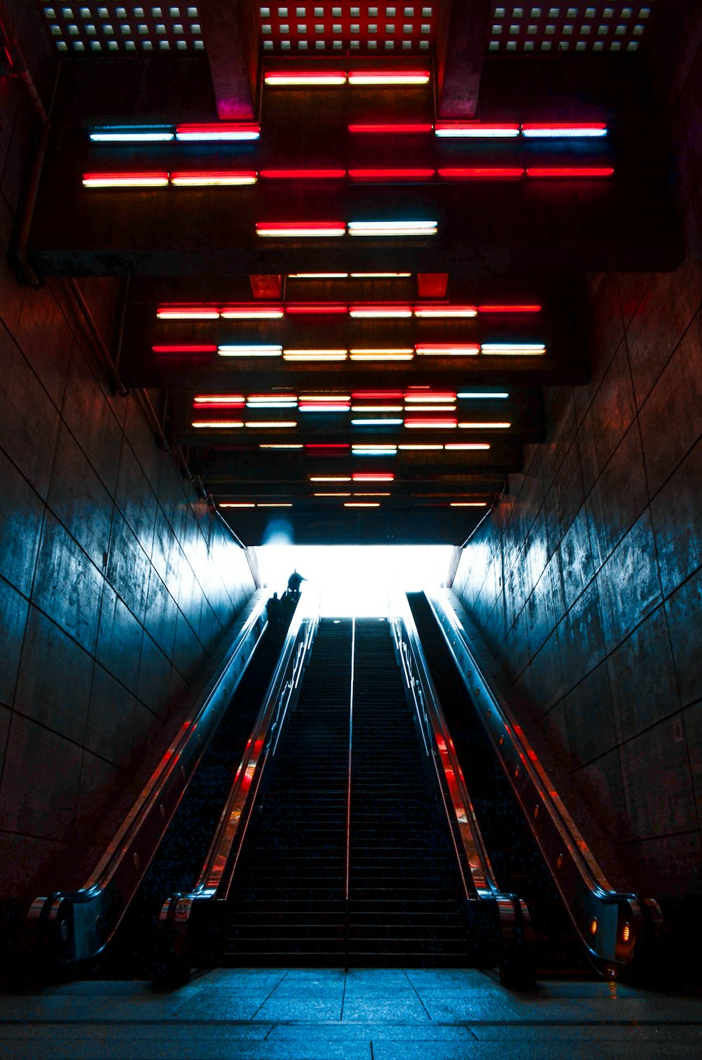 an escalator in a building with red and blue lights