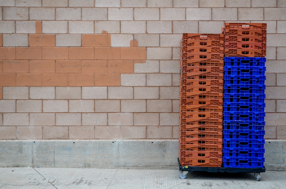 a blue and orange cart sitting next to a brick wall