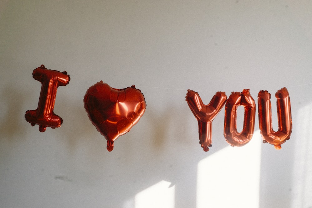 balloons spelling out i love you in front of a white wall
