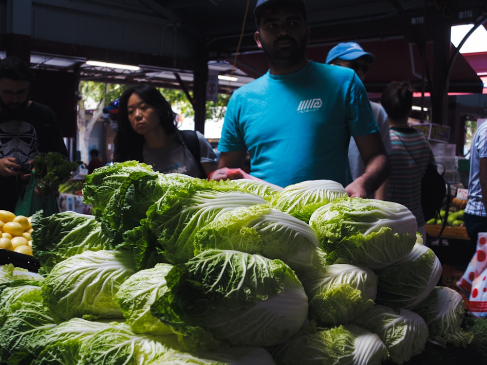 a man standing in front of a pile of lettuce