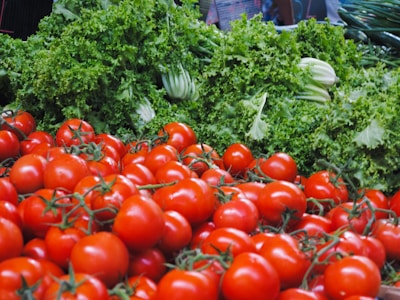 Close-up of ripe tomatoes and leafy greens ready for sale.