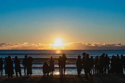A group of travelers breathing deeply by the serene Caribbean sea at sunrise.