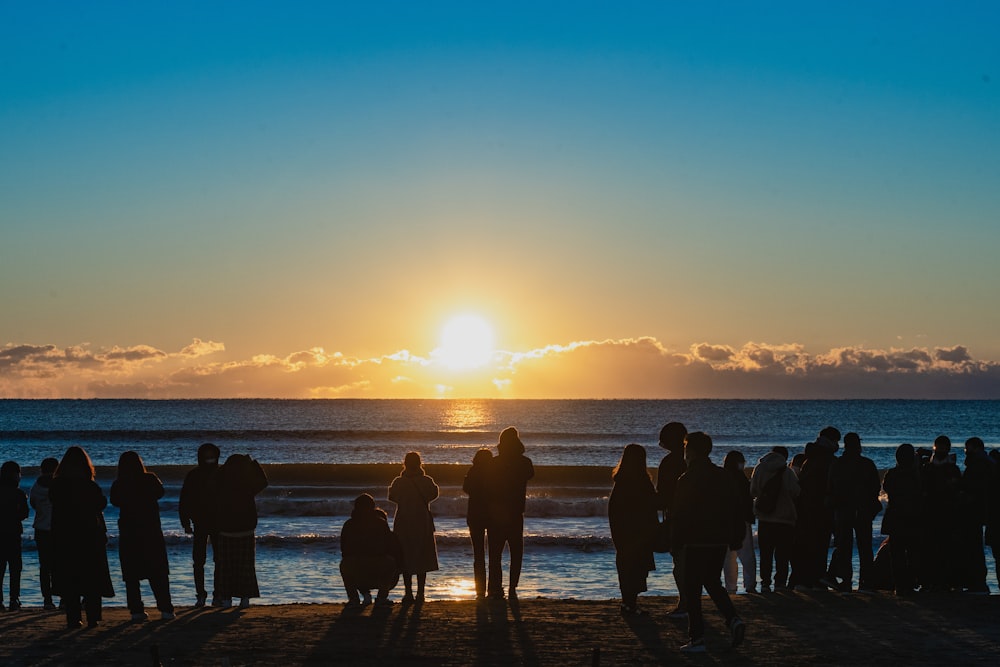 a group of people standing on top of a beach