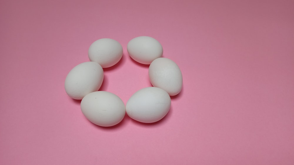 a group of white eggs sitting on top of a pink surface