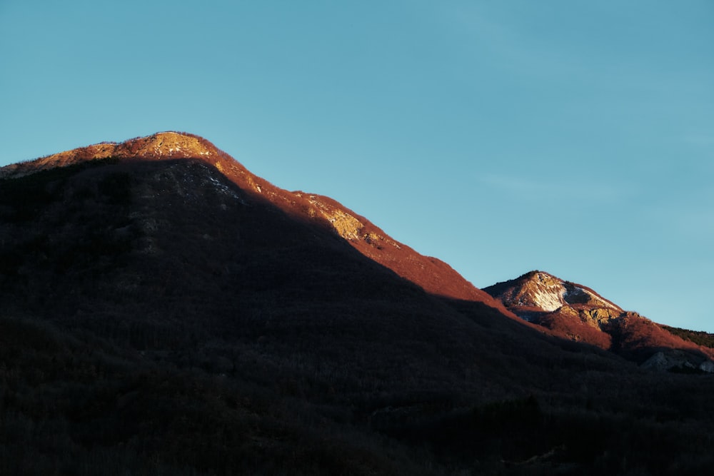 the sun is setting on a mountain peak