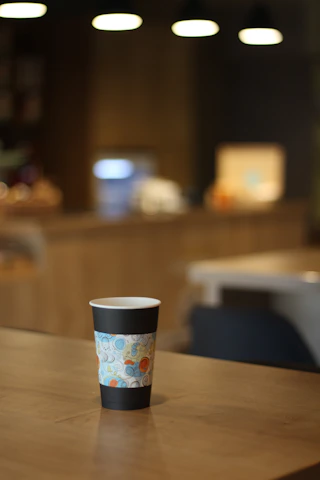 Colorful workspace showing eco-friendly printed plastic cups with vibrant designs on a wooden table.