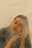 A person with eyes closed and a serene expression, with a hand resting on the side of the face, surrounded by a soft haze that creates a tranquil and dreamy atmosphere.