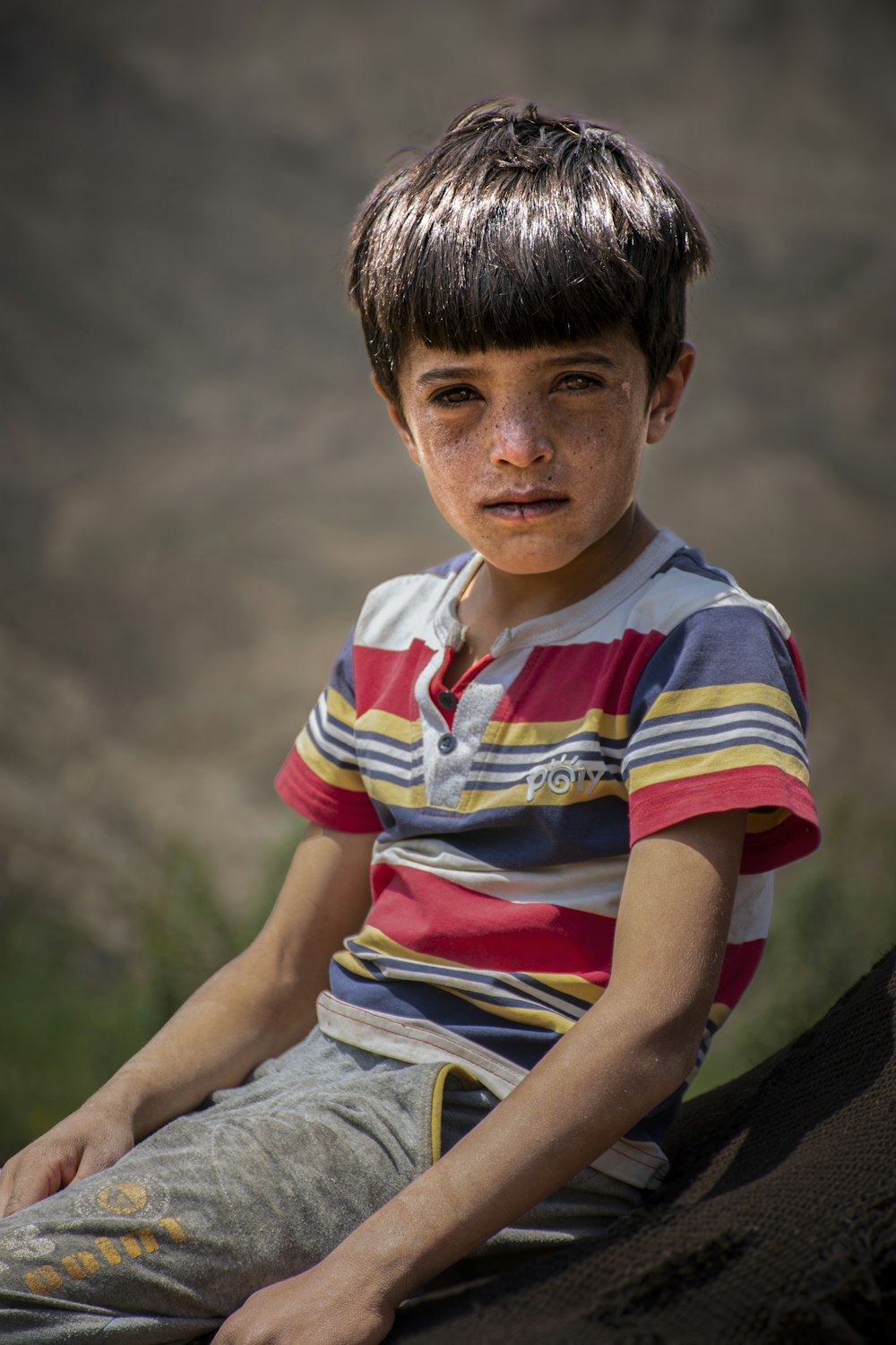 a young boy sitting on top of a rock