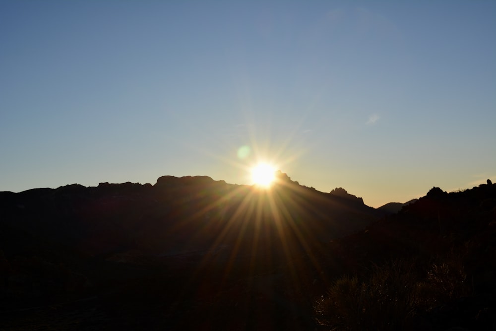 the sun is setting over a mountain range