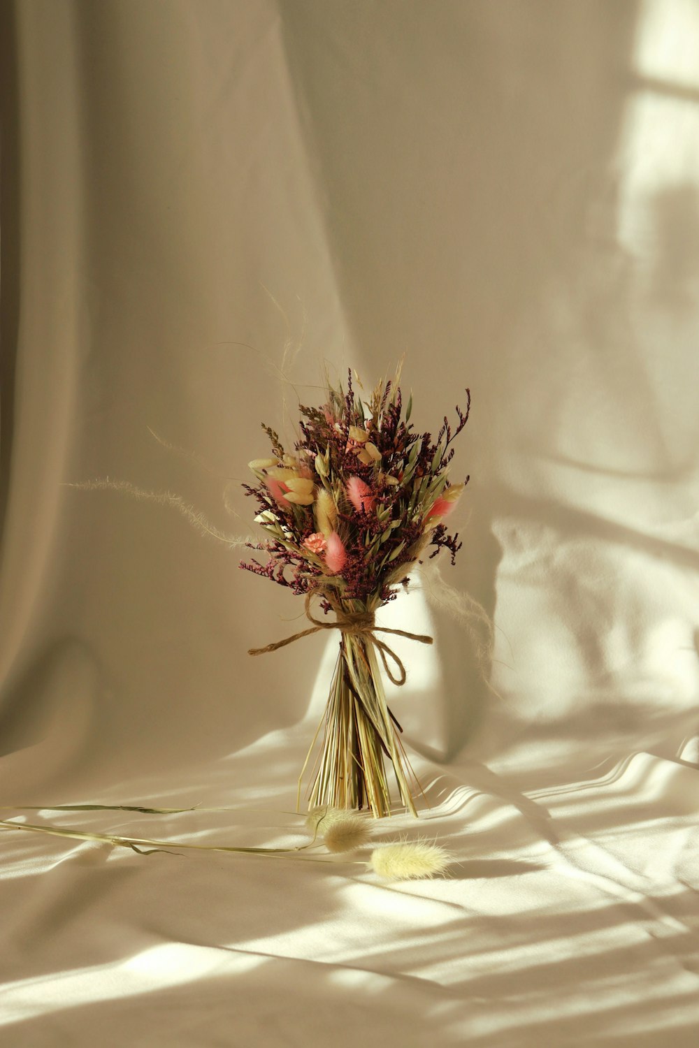 a bouquet of dried flowers sitting on top of a white sheet