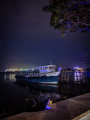A welcoming Amazonian river scene at sunset with a small wooden boat tied to a dock near lush vegetation.