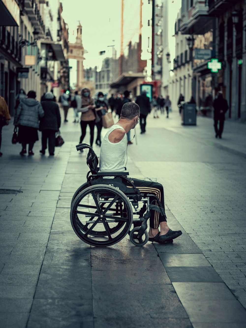 un homme en fauteuil roulant assis sur un trottoir