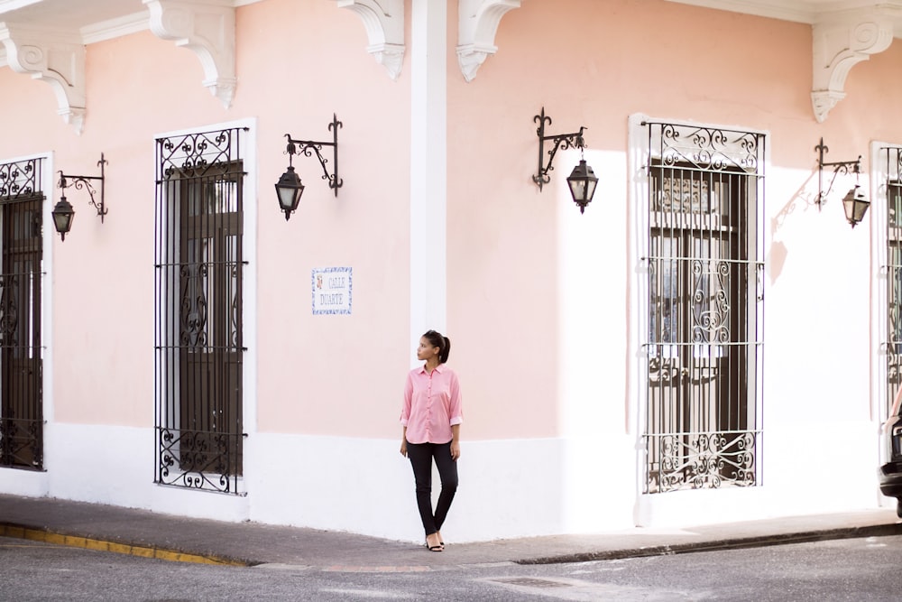 a woman standing in front of a pink building