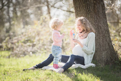 a woman and a child sitting under a tree