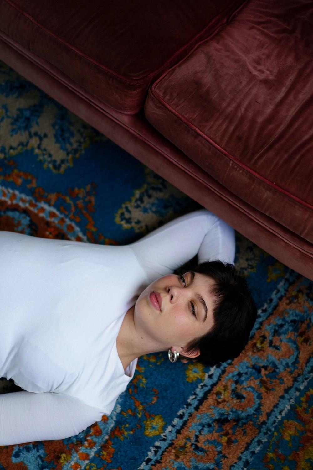 a woman laying on the floor next to a couch