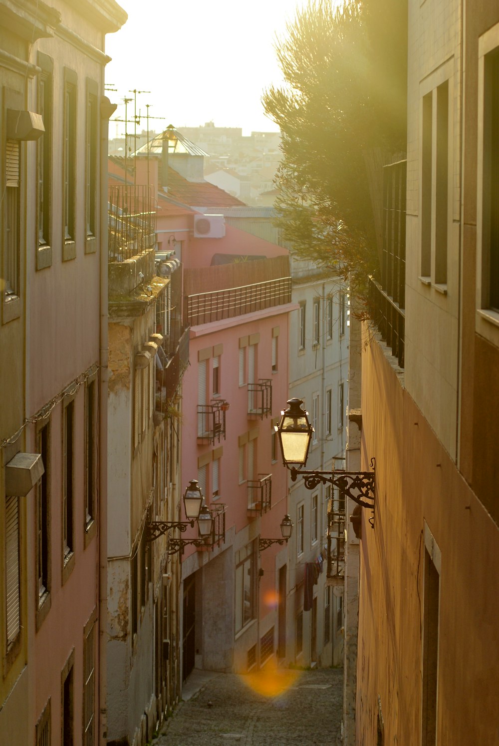 the sun is shining down on a narrow city street