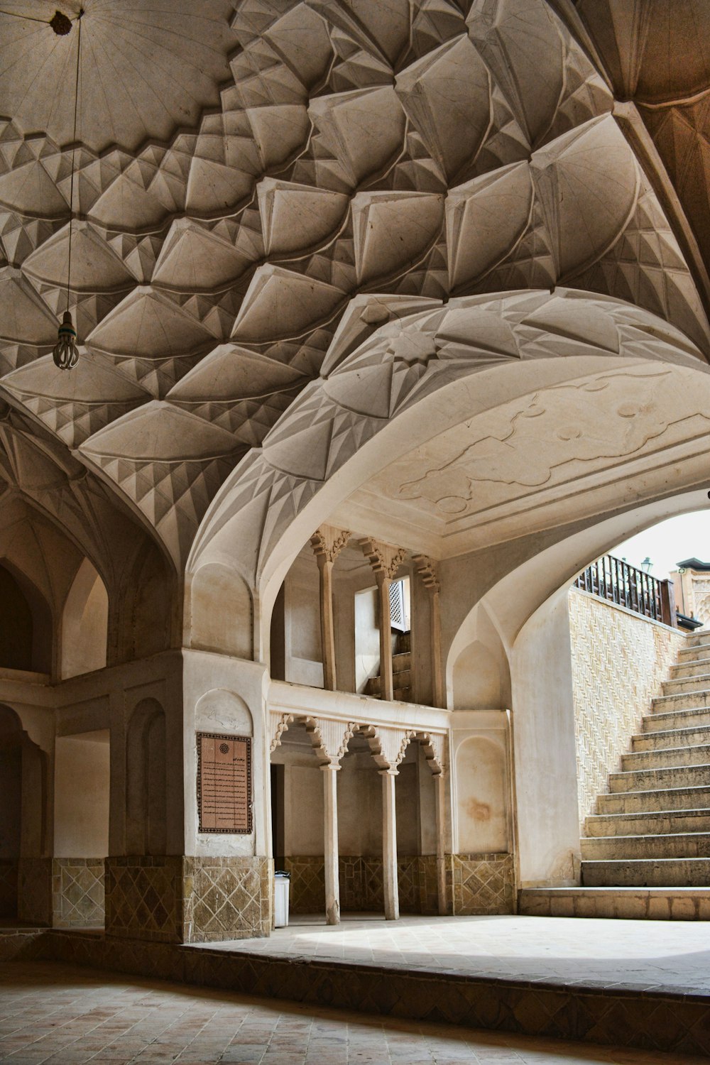 uma grande sala com uma escadaria e uma parede de pedra