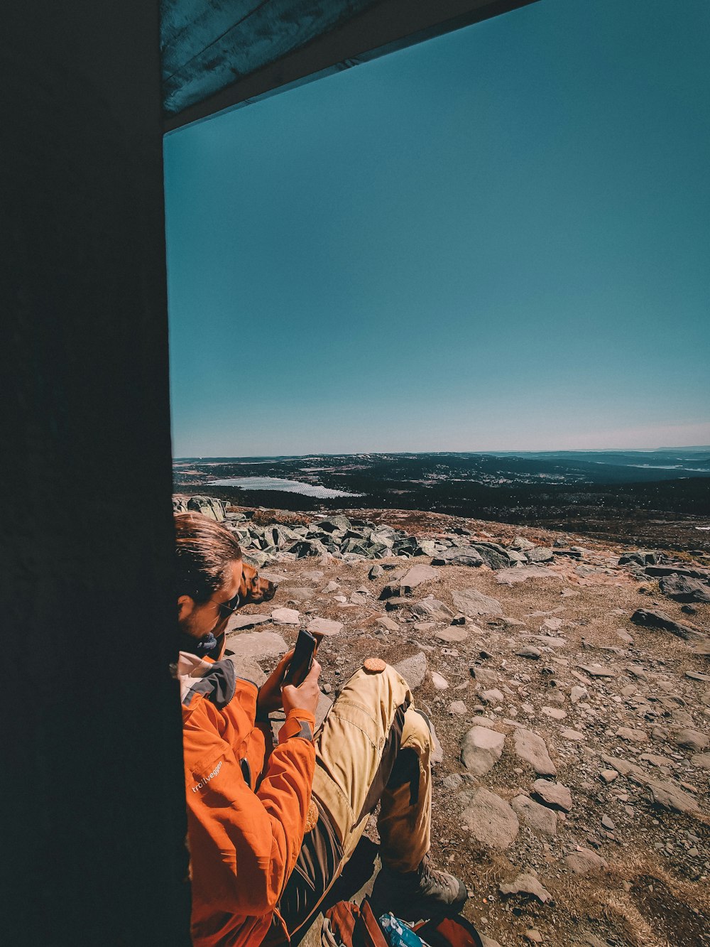 a man sitting on top of a rock covered hillside