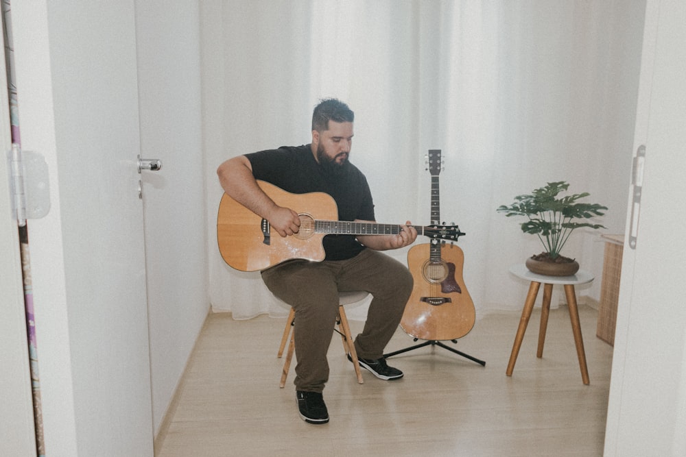 a man sitting on a chair playing a guitar