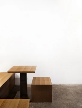 A minimalist light gray wooden table set against a white wall.