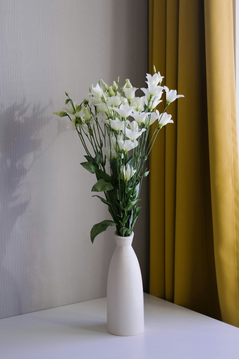 a white vase filled with white flowers on top of a table