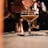 Close-up of a hand pouring premium spirit into a glass over a wooden bar counter.