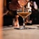 Close-up of a hand pouring premium spirit into a glass over a wooden bar counter.
