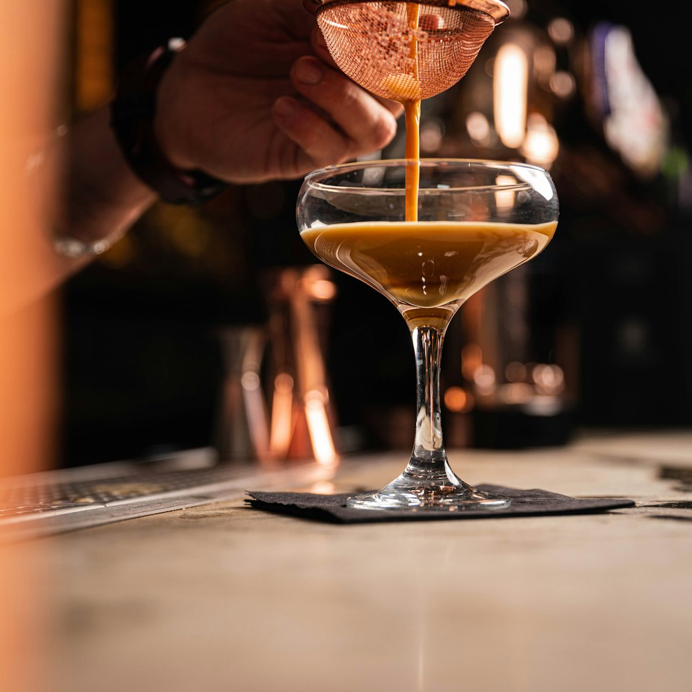 a person pouring a drink into a glass