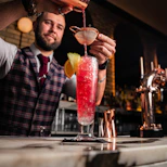 a man pouring a drink into a tall glass