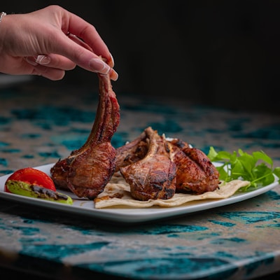a person holding a piece of meat on a plate