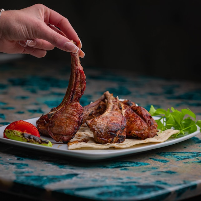a person holding a piece of meat on a plate