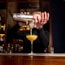 Close-up of a bartender's hands skillfully mixing a cocktail at a sleek bar counter.