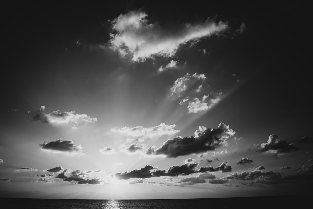 a black and white photo of the sun shining through the clouds