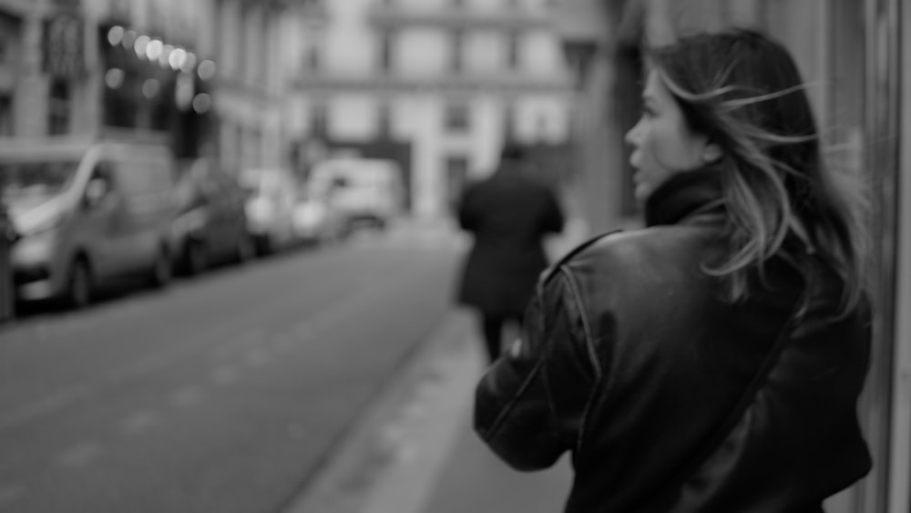 a woman standing on the side of a street next to a building