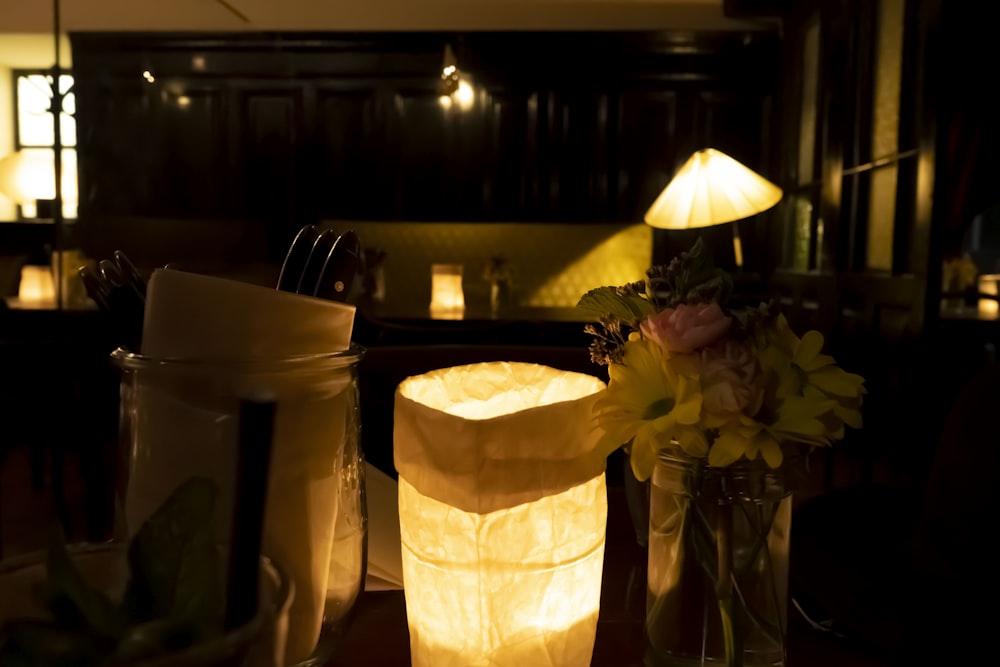 a table with a vase of flowers and a lit candle