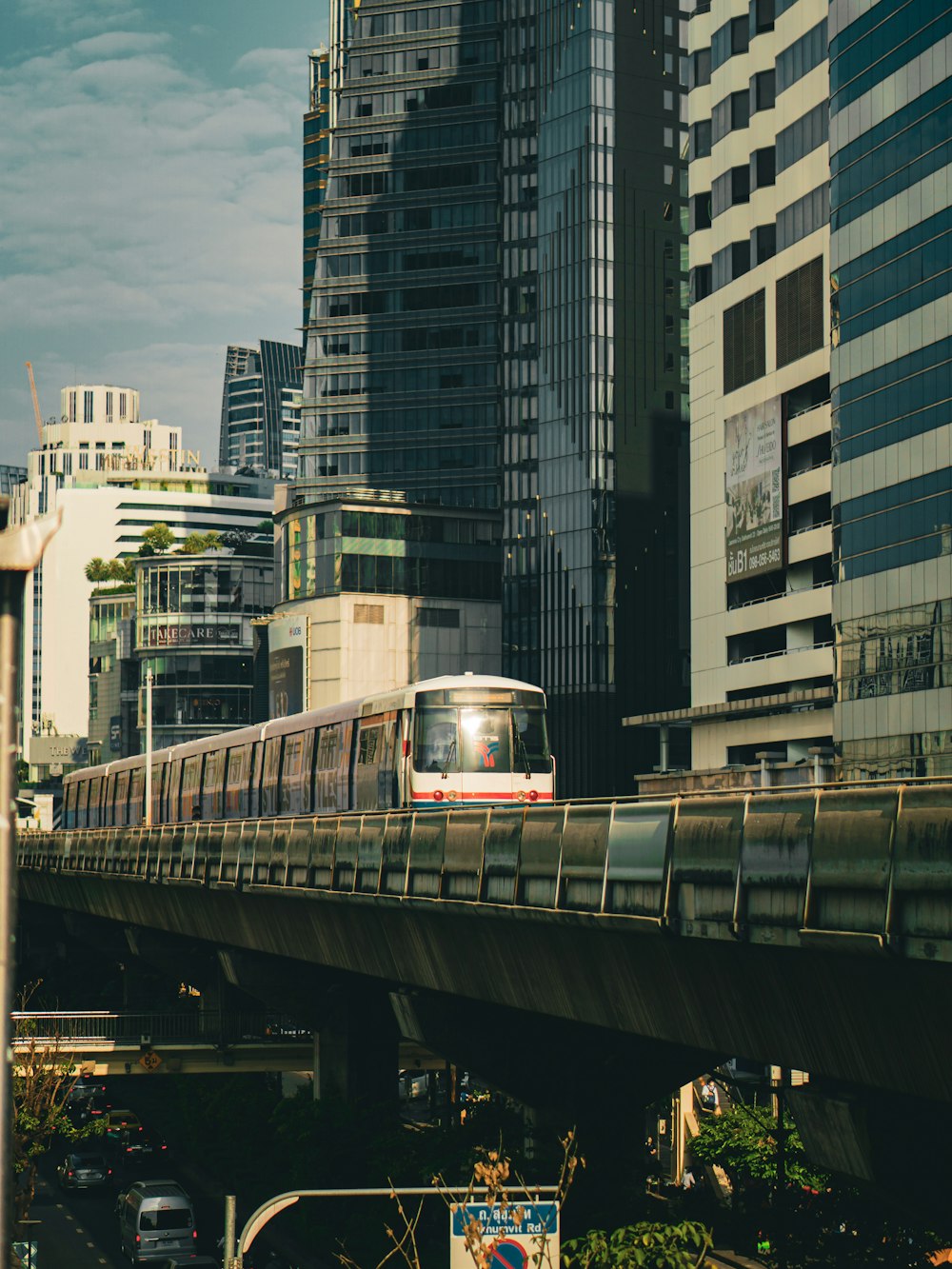 a train traveling over a bridge with tall buildings in the background
