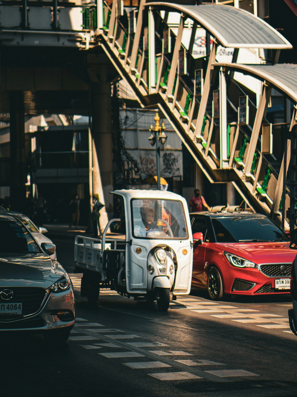 a small car driving down a street next to a bridge