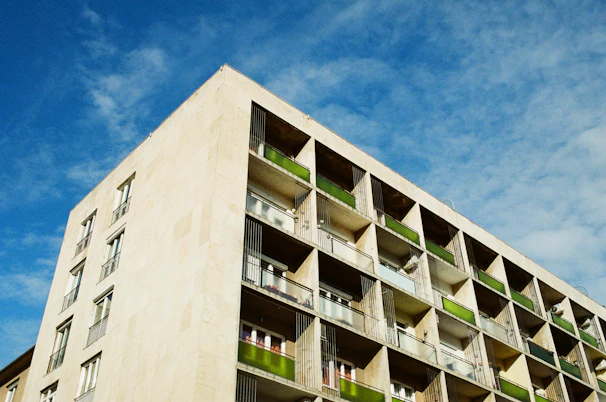 Completed residential building with clean lines and balconies, set against a sunset.